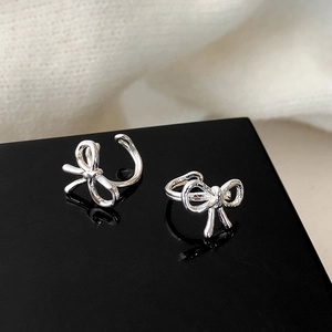 Elegant silver bow ear cuff set with a minimalist polished wrap design on black acrylic