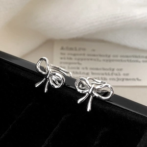 Minimalist silver bow knot earrings displayed on black velvet for an elegant look