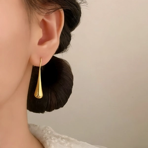 Elegant gold teardrop hook earrings with polished finish shown on a model