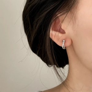 Élégantes créoles torsadées en argent serties de zircons portées par un mannequin