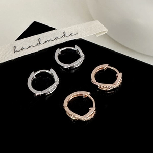 Élégantes boucles d'oreilles créoles croisées en pavé argent et or rose sur support noir