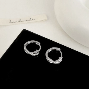 Détail macro de créoles en argent serties de zircons sur un support de bijoux noir