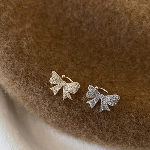 Detail of bow-shaped ear cuffs with micro-set zircons in gold and silver finishes
