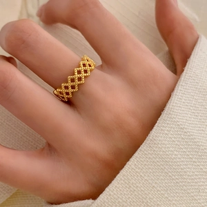 Adjustable hollow geometric gold lattice ring worn on hand with cream knit sweater
