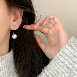 Elegant pearl drop earrings worn by a model in a minimalist French style daily setting