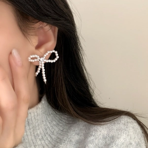 Boucles d'oreilles nœuds en perles avec centre en cristal portées par un modèle