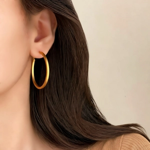 Minimalist matte gold flat hoop earrings with wide geometric design worn by a model