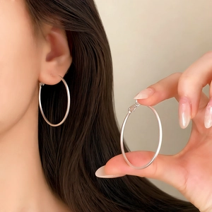 Macro detail of large silver hoop earrings showcasing smooth finish and round geometric design