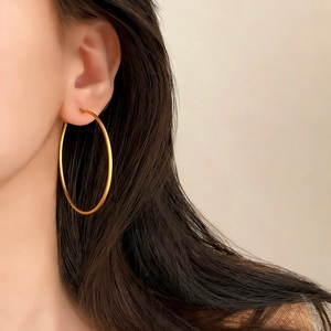 Macro side view of a large golden minimalist hoop earring worn for an elegant look