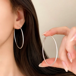 Detail of silver geometric hoop earrings featuring minimalist matte finish on model and hand