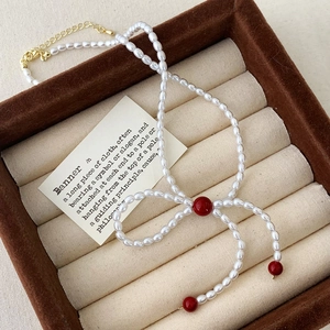 Gros plan d'un collier nœud en perles avec perles rouges sur une boîte à bijoux