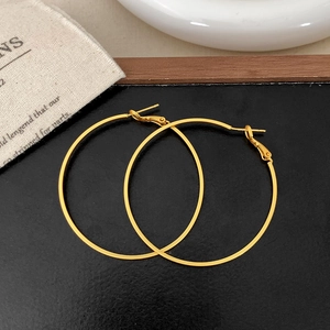 Detailed view of large gold hoop earrings on a textured black leather background