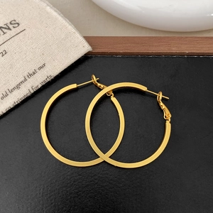Detail of gold geometric hoop earrings with flat square edges on a premium display