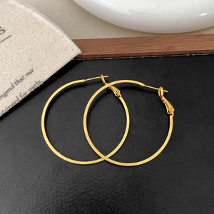 Detailed view of large golden hoop earrings with high-polish finish on natural linen