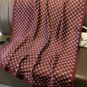 Detailed shot of dark red silk scarf with geometric pattern on brown leather couch