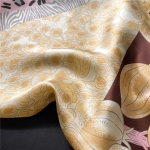 Detail of silk-like satin scarf with golden plant patterns and zebra print borders