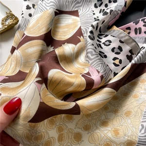 Close-up of silk-like satin square scarf with leopard print and floral patterns