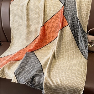 Detailed texture of large silk-feel scarf with geometric patterns and chic color blocks