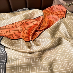 Macro shot of geometric pattern silk scarf draped over a luxury leather handbag