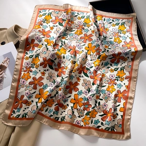 Close-up of floral pattern satin square scarf on trench coat showing silk texture