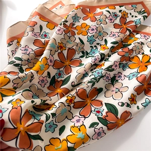 Detail of vintage floral silk scarf with orange border and pastel flower patterns