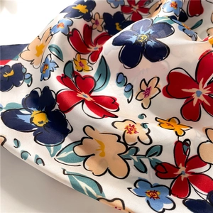 Detail of silk-like square scarf featuring vibrant red and navy blue floral prints