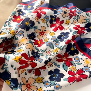 Close-up of floral print silk scarf with multi-colored flowers and contrast borders