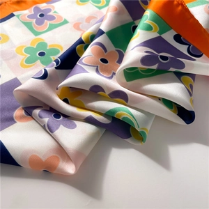Close-up of floral checkerboard silk scarf with vibrant orange and purple satin texture