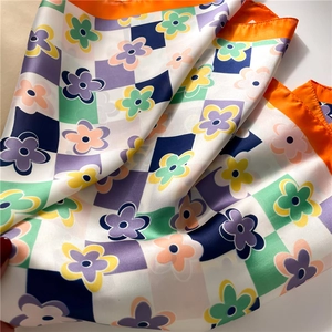 Detailed view of floral checkerboard silk scarf with satin finish and orange borders