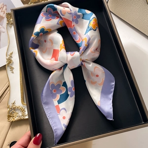 Detail of silk-like floral square scarf with purple accents inside a premium gift box