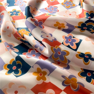 Detailed macro view of vibrant floral checkerboard pattern on smooth satin fabric