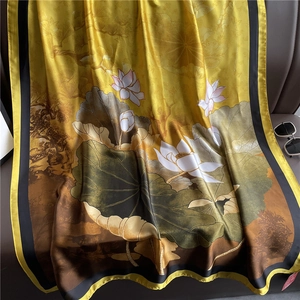 Detail of elegant yellow silk scarf with lotus print and black borders on leather chair