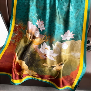 Luxurious emerald green silk scarf with lotus pattern draped over a leather chair