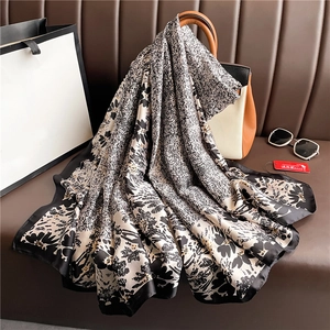 Luxurious large floral print silk scarf in black and white hanging on a stylish handbag