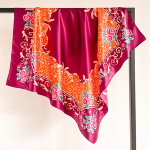 Détail d'un foulard en satin fleuri montrant la texture soyeuse sur un support noir