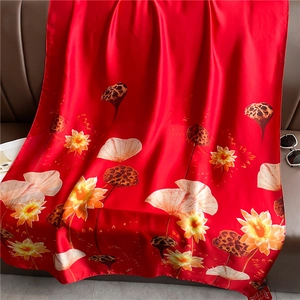 Detailed view of luxury red silk shawl with artistic lotus pattern on leather background