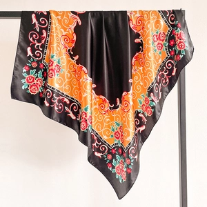 Détail d'un foulard en satin montrant la texture lisse et les motifs roses orange