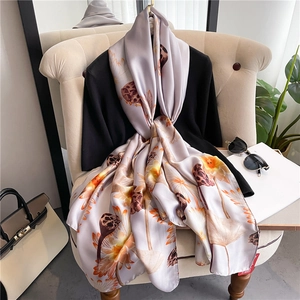 Elegant purple silk scarf with orange lotus patterns draped over a stylish armchair