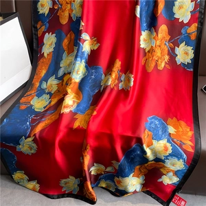 Detail of red silk scarf with blue lotus patterns and black edges draped elegantly