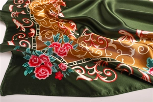 Gros plan détaillé d'un foulard en satin aux motifs floraux rouges et lianes vertes
