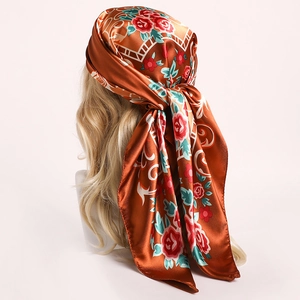 Détail d'un foulard en soie noué sur la tête avec motifs de roses orange et vignes