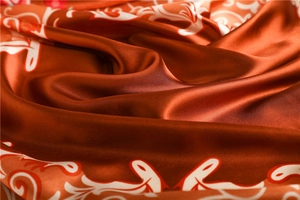 Détail macro du foulard en satin de soie avec motifs floraux élégants et texture brillante