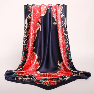 Détail du foulard en satin soyeux avec volutes dorées et fleurs rouges sur fond marine