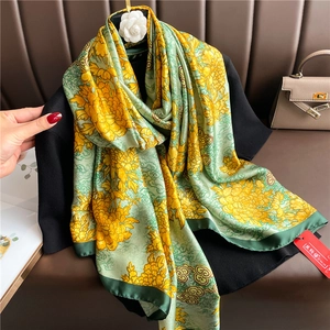 Detail of silk scarf showing yellow chrysanthemum and green cloud patterns on satin fabric