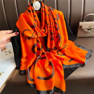 Detail of silk scarf with orange letter patterns, black borders and camellia ornament