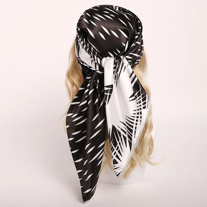 Ink style satin headscarf with black and white leaf patterns on a golden mannequin head