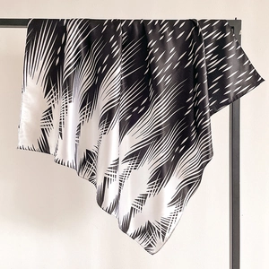 Detail of satin scarf with monochrome geometric ink pattern hanging on minimalist metal rack