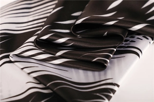 Detailed view of satin silk scarf with black ink wave pattern and high gloss texture
