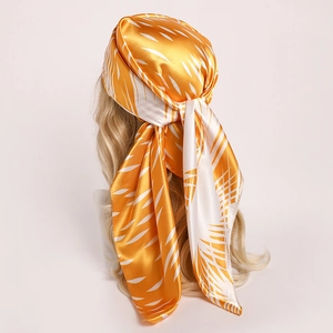 Detail of satin silk scarf tied as a headband showing yellow leaf patterns and glossy texture