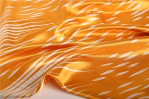 Detailed view of silky satin scarf fabric with orange and white wavy ripple patterns